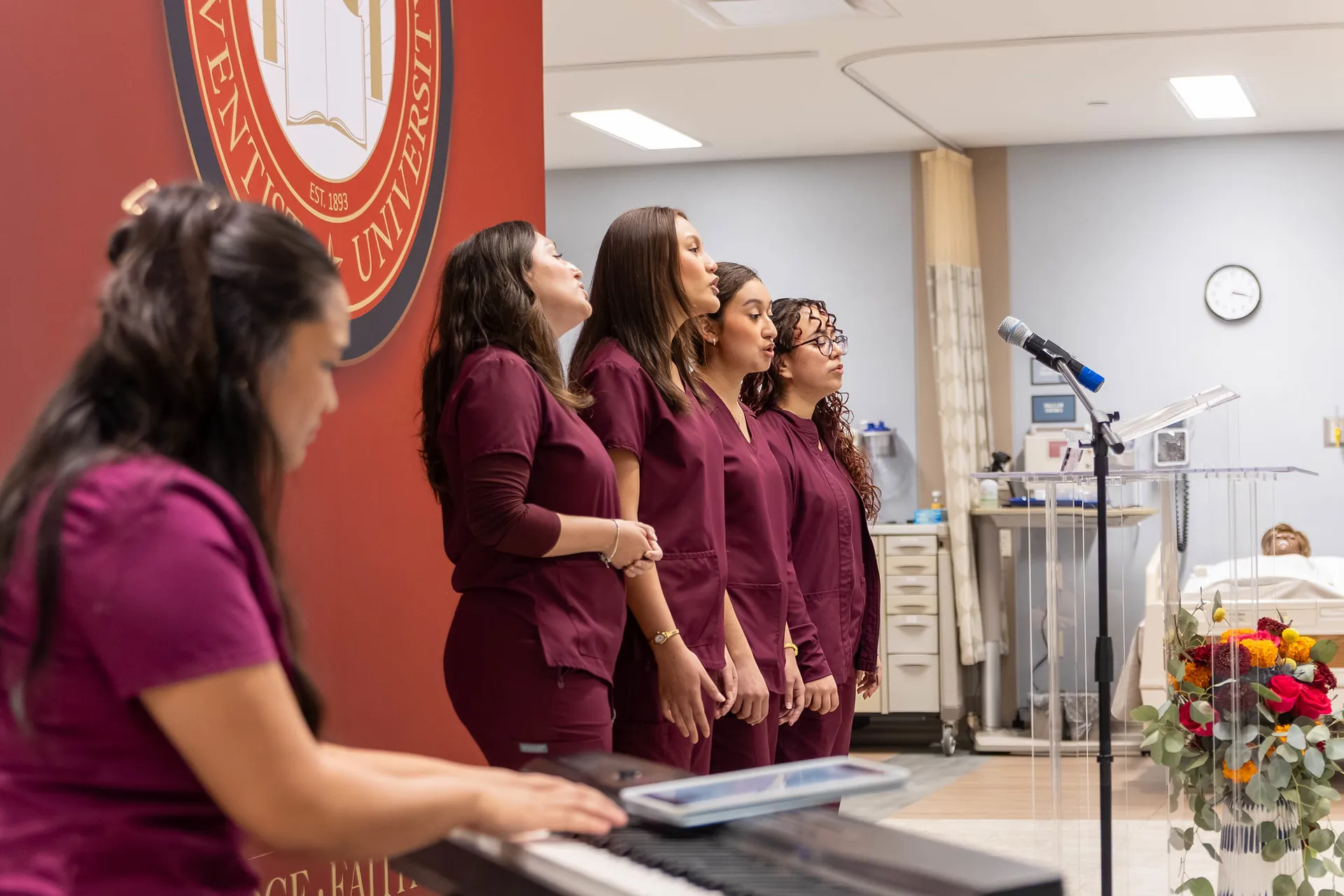 Four Nursing students singing while one plays piano
