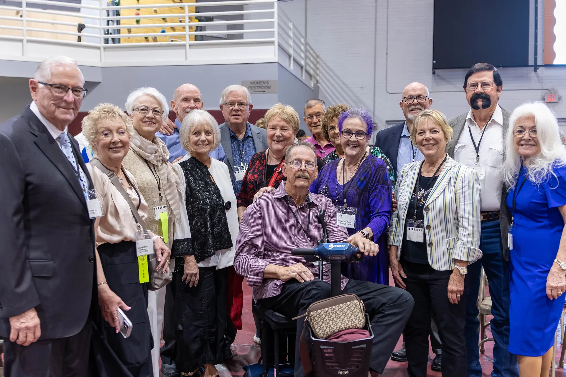 A group of older alumni crowded together for a photo