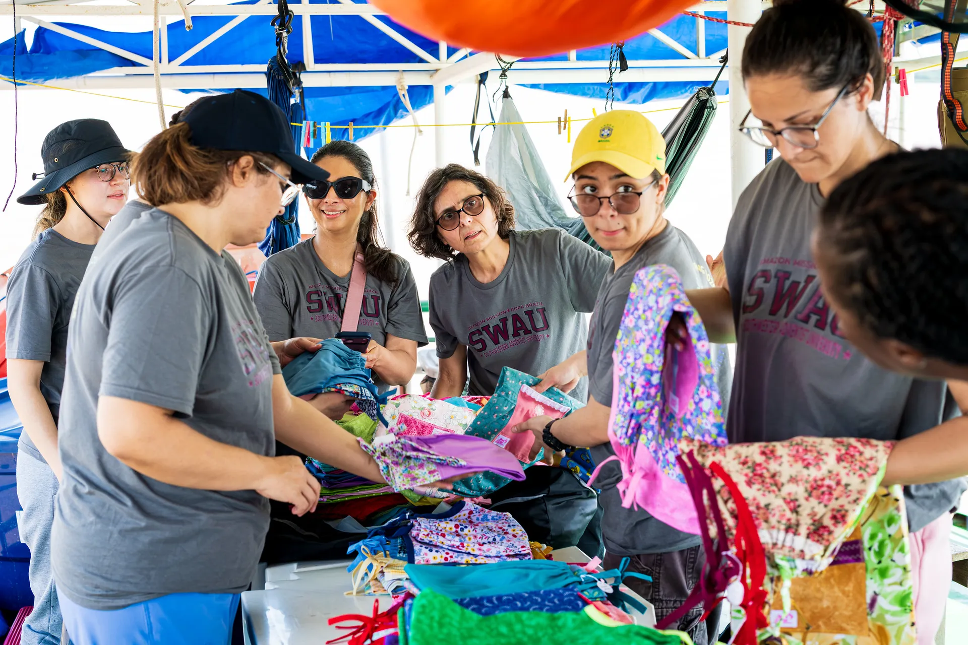 people standing around a thin table, sorting clothes