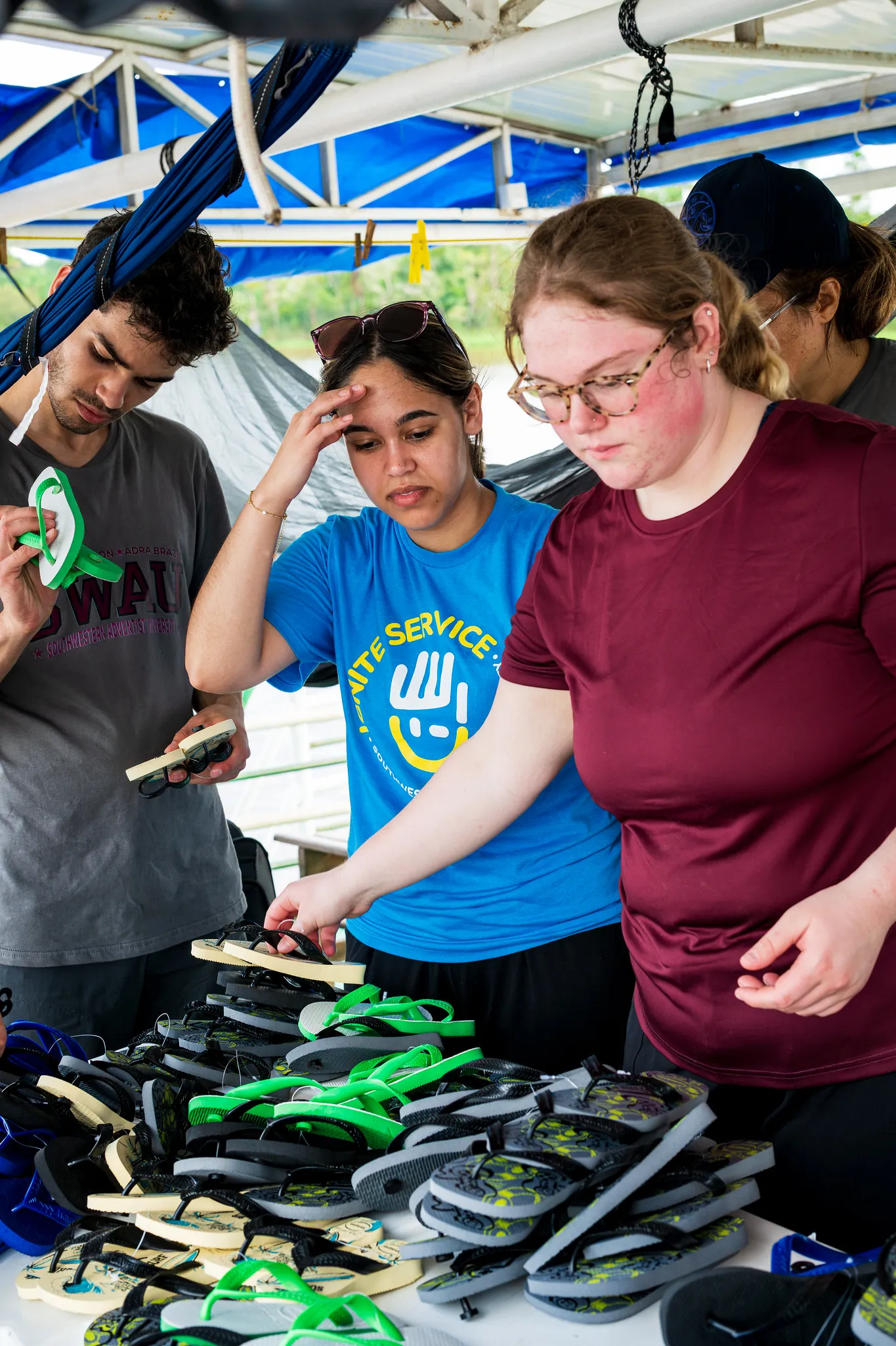 Three people going through a large pile of sandals