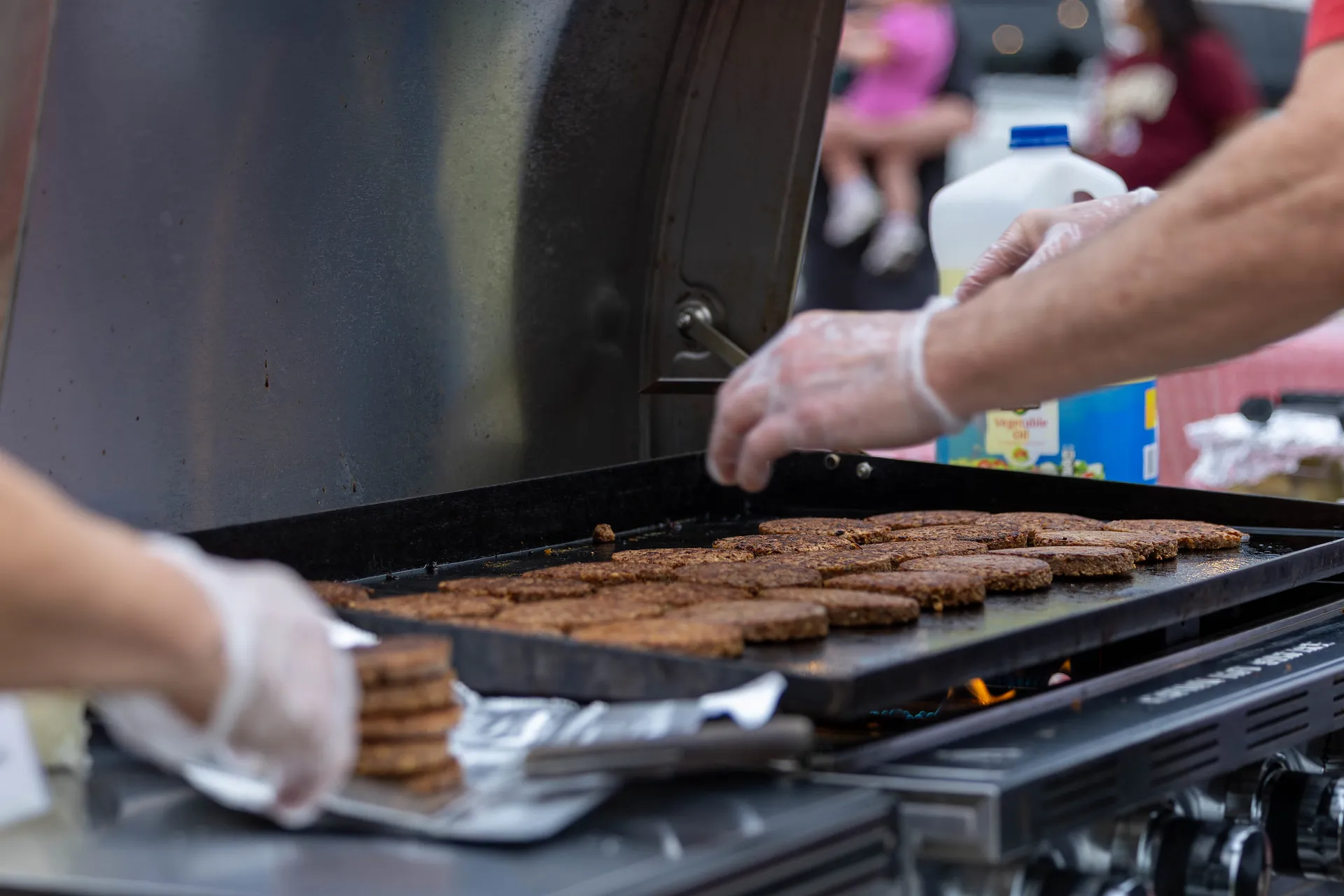 Burger patties neatly lined up on an outdoor grill