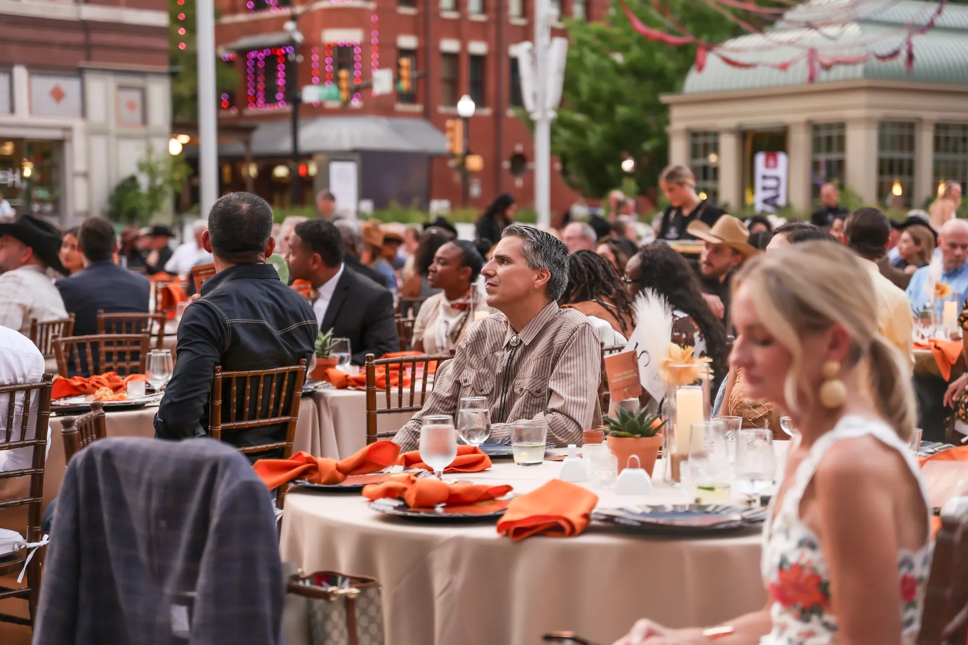 Man at dinner table in crowd looking into distance