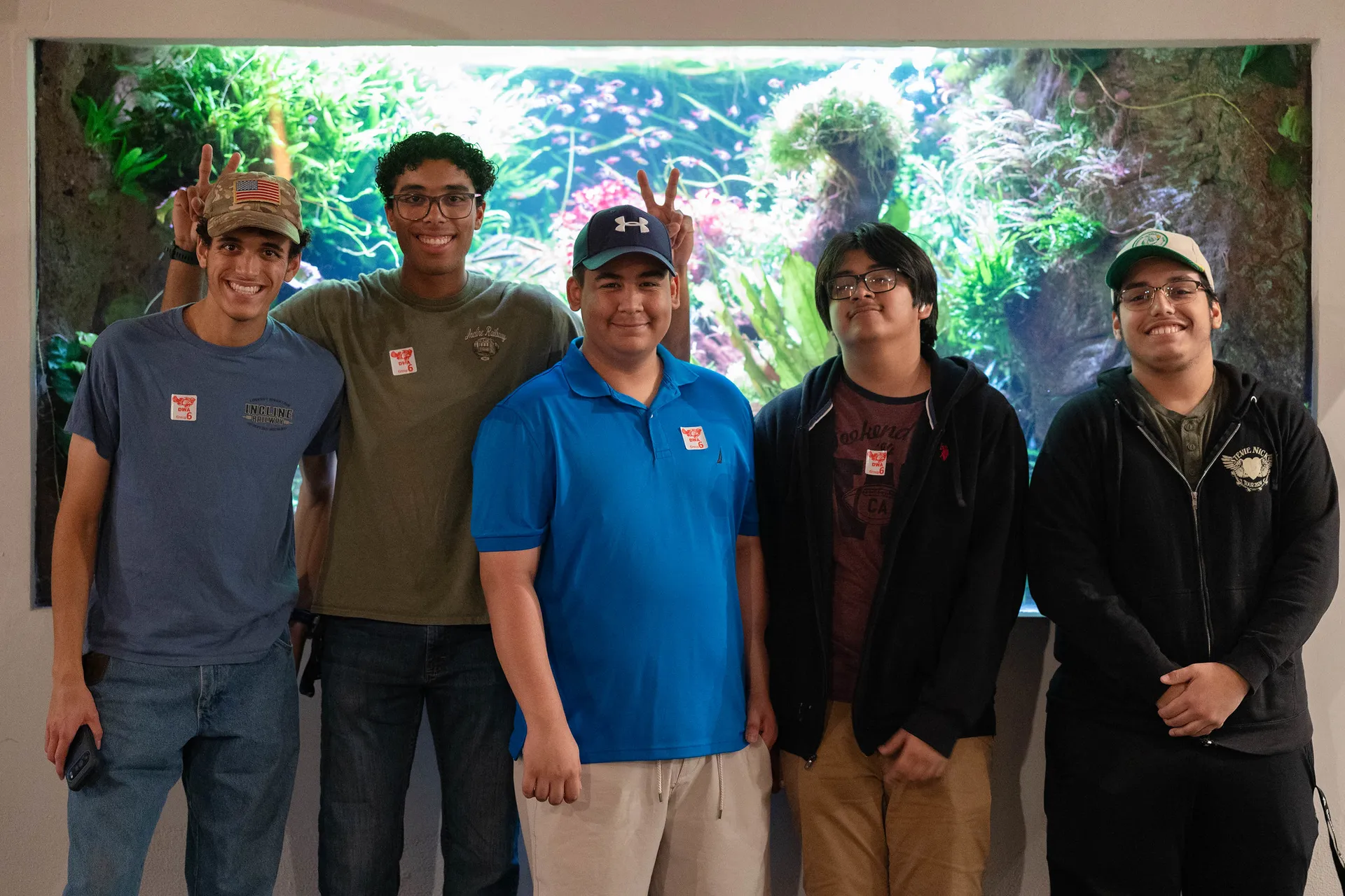 five boys standing in a line smiling in front of a zoo exhibit