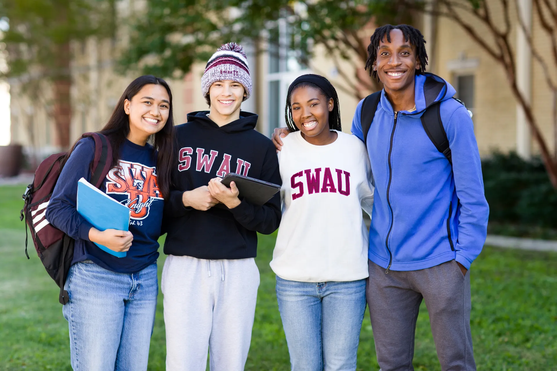 4 students standing in front of Miller dorm smiling