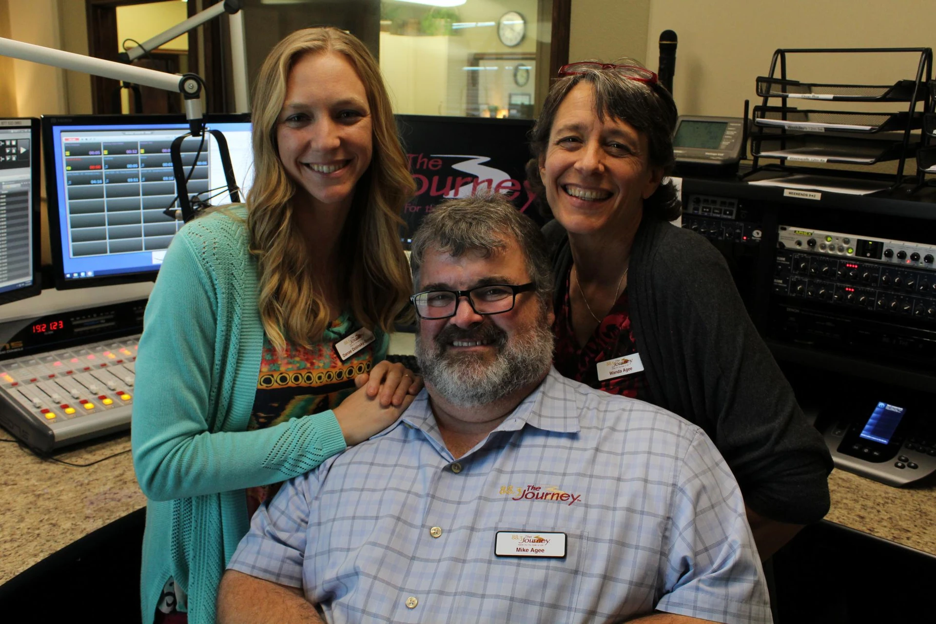 Danae Songy and Wanda Agee posing behind Mike Agee inside the radio station