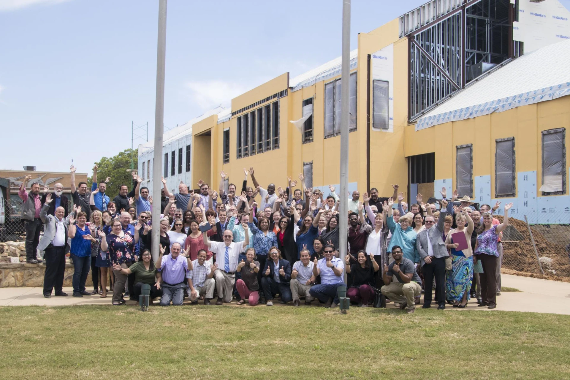 All the faculty and staff of SWAU stand in several rows in front of the new nursing building that is being built behind them